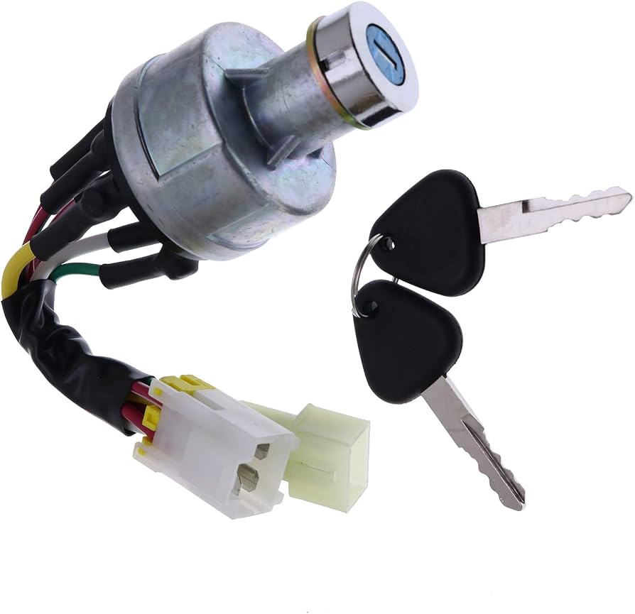 A metal ignition switch for heavy machinery with a wiring harness and two black-handled keys on a ring.