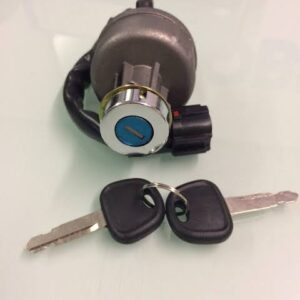 A metal ignition switch for heavy machinery with a blue keyhole and two black plastic-headed keys attached to a ring.