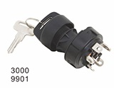 A black ignition switch for heavy machinery with a metal key inserted and electrical terminals visible on the back.